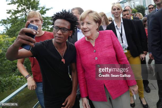 German Chancellor Angela Merkel pauses for a selfie with a young man who came alone as a refugee from Eritrea to Germany among visitors during the...