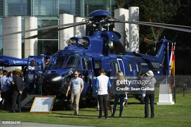 Visitors look at a helicopter of the German federal police force during the annual open-house day at the Chancellery on August 27, 2017 in Berlin,...
