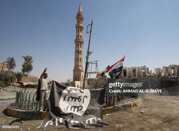 Fighters from the Hashed al-Shaabi , backing the Iraqi forces, pose for a photograph with a flag of the Islamic State group in Tal Afar's Qalea...