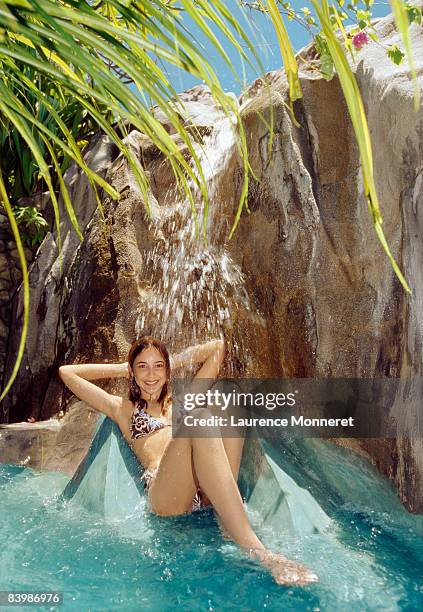 young smiling girl sitting under a small waterfall - fregate stock pictures, royalty-free photos & images