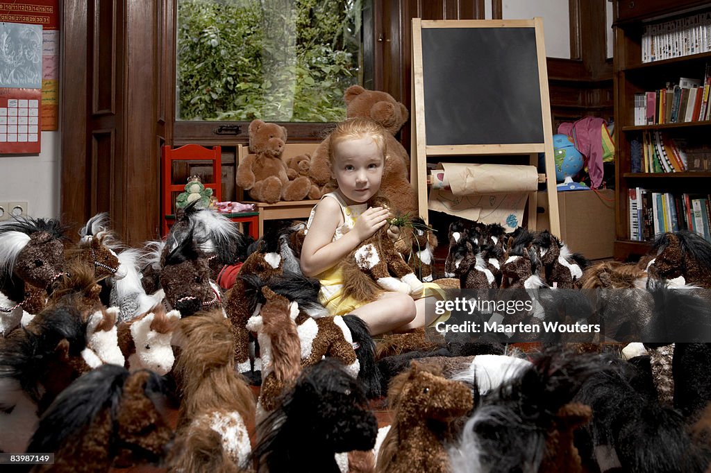 Portrait of a girl among her toy horses