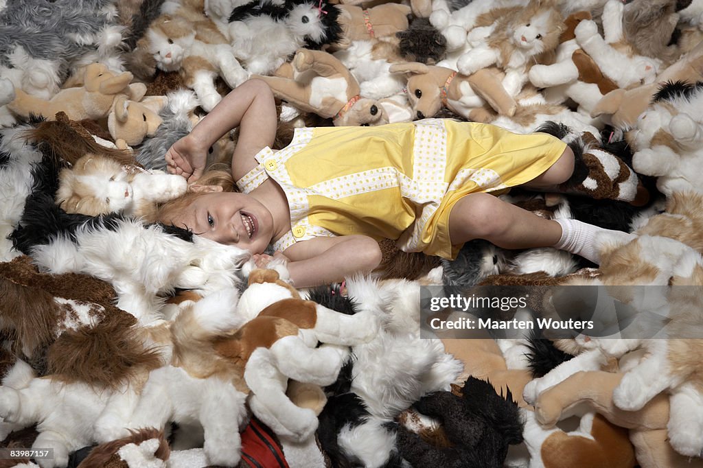 Girl lying down on a big pile of stuffed toys