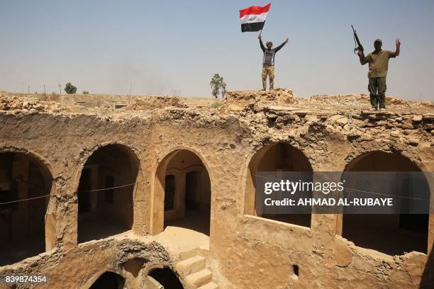 Fighters from the Hashed al-Shaabi , backing the Iraqi forces, pose with the Iraqi flag from Tal Afar's Ottoman-era historic citadel after troops...