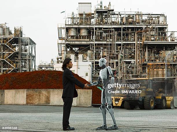 robot and human greeting in front of factory - fantasy factory stock pictures, royalty-free photos & images