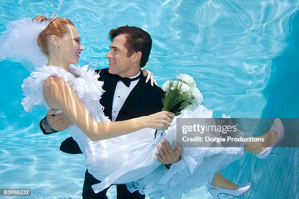 groom carries his bride underwater - bride underwater stock pictures, royalty-free photos & images