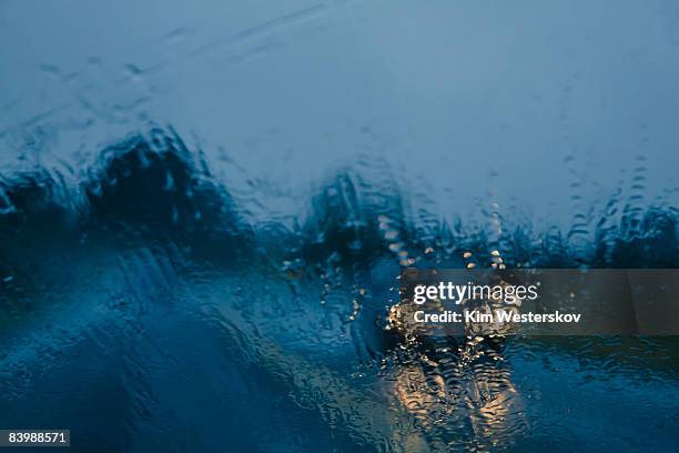 approaching car through wet windscreen, headlights - westerskov stock pictures, royalty-free photos & images