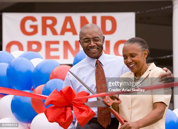 couple cutting ribbon at grand opening celebration - black ribbon stock pictures, royalty-free photos & images