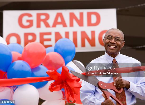 man cutting ribbon at grand opening celebration - opening ceremony stock-fotos und bilder