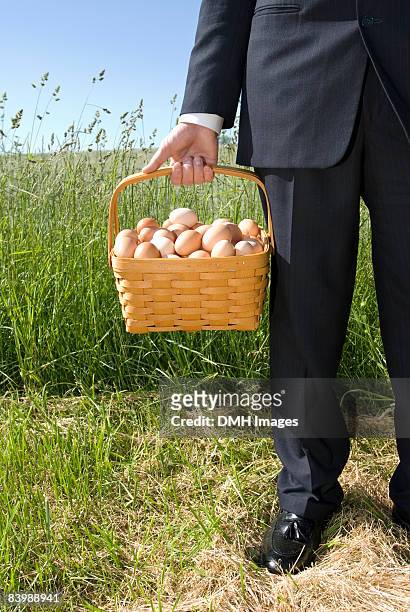 business man holding basket of eggs. - eggs in basket stock pictures, royalty-free photos & images