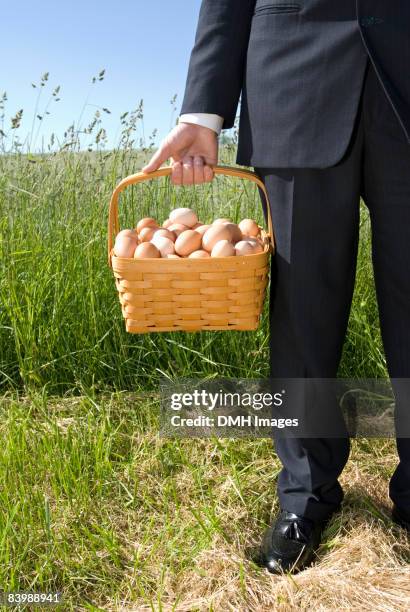 business man holding basket of eggs. - eggs in a basket stock pictures, royalty-free photos & images