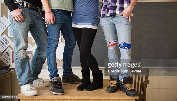 four teens standing upon teachers desk in class - blackboard qc stock-fotos und bilder