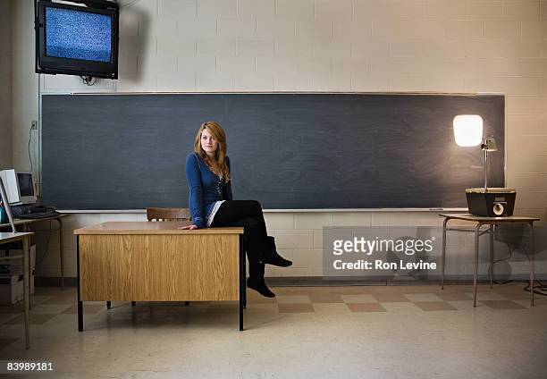 teen girl sitting on teacher's desk in classroom - blackboard qc stock pictures, royalty-free photos & images