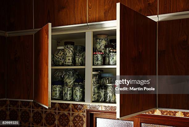 jars of 100 dollar bills in open kitchen cupboards - hiding money stock pictures, royalty-free photos & images