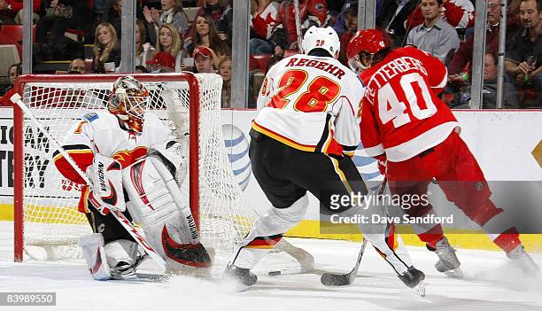 Henrik Zetterberg of the Detroit Red Wings battles for the rebound with Robyn Regehr of the Calgary Flames as Curtis McElhinney of the Calgary Flames...