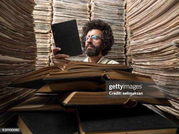 hombre adulto con pelo oscuro libro de lectura en el archivo de medios impresos - registro fotografías e imágenes de stock
