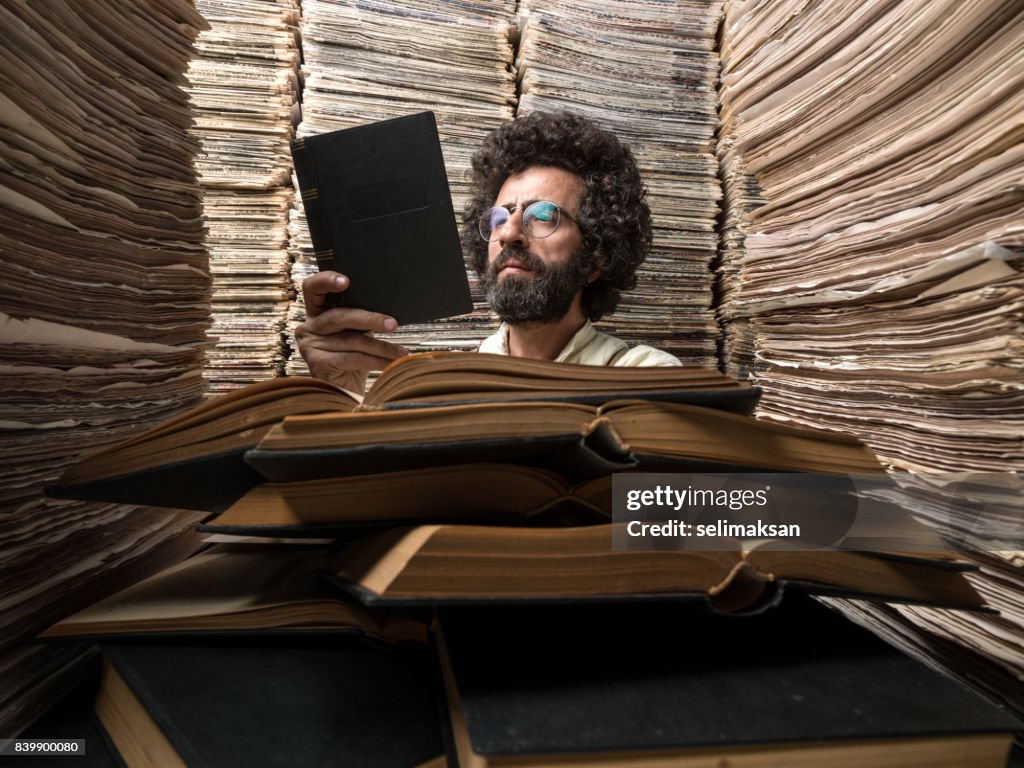Adult Man With Dark Hair Reading Book In Printed Media Archive