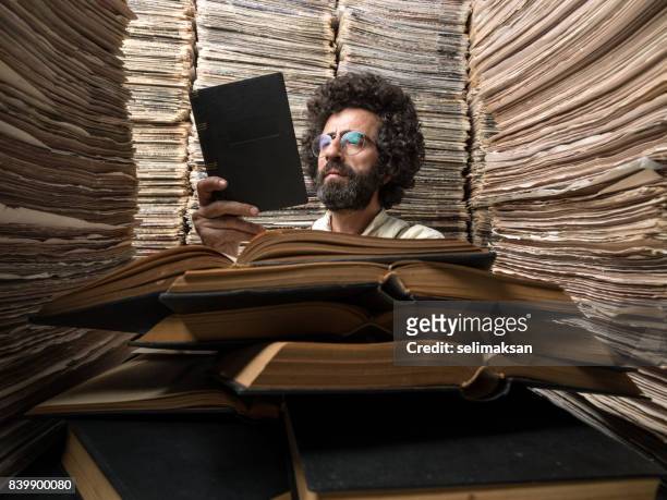 adult man with dark hair reading book in printed media archive - history stock pictures, royalty-free photos & images