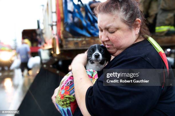Elma Moreno comforts her dog, Simon as they are loaded on to a trucks after being evacuated from their flooded apartment. Tropical Storm Harvey is...
