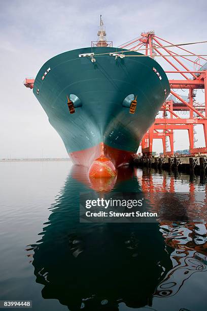 bow of a red and teal cargo ship. - containerschip stockfoto's en -beelden