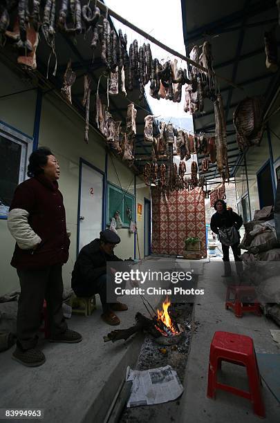 Earthquake survivors make preserved meat for the upcoming Chinese new year at a temporary settlement on December 10, 2008 in Wenchuan County of...