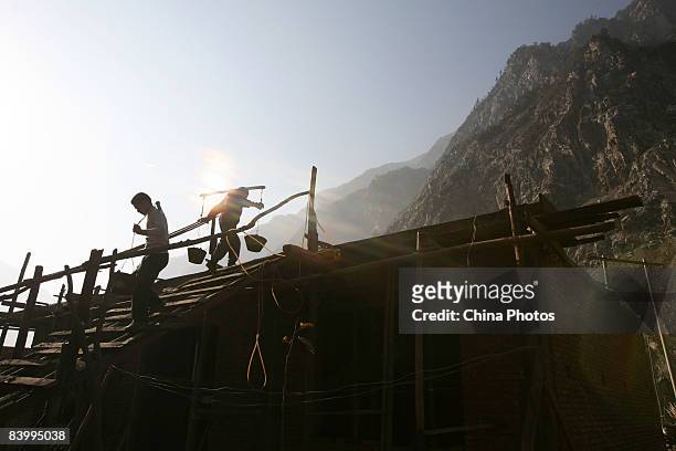 Survivors of the May 12 Sichuan Earthquake carry cement to rebuild a house at the Yingxiu Township on December 11, 2008 in Wenchuan County of Sichuan...