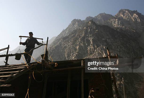 Survivor of the May 12 Sichuan Earthquake carries cement to rebuild a house at the Yingxiu Township on December 11, 2008 in Wenchuan County of...