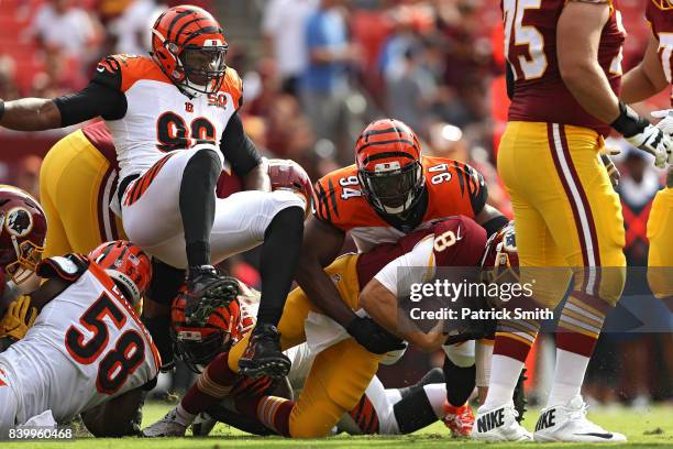 Quarterback Kirk Cousins of the Washington Redskins is sacked by defensive end Chris Smith and defensive end Wallace Gilberry of the Cincinnati...