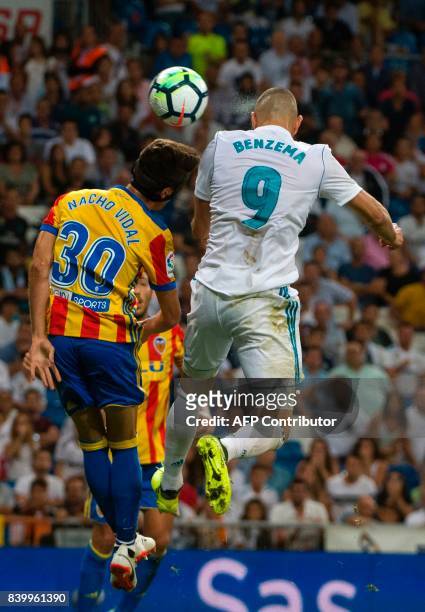 Valencia's midfielder Nacho Vidal jumps for the ball with Real Madrid's French forward Karim Benzema during the Spanish league football match Real...