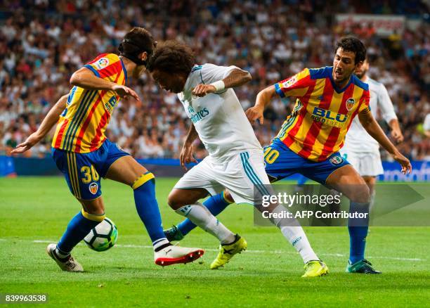 Real Madrid's Brazilian defender Marcelo vies with Valencia's midfielder Nacho Vidal and Valencia's midfielder Daniel Parejo during the Spanish...