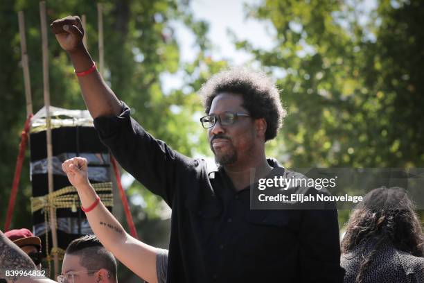 Comedian W. Kamau Bell raises his fist from a truck as people begin to march from MLK Jr. Park on August 27, 2017 in Berkeley, California.