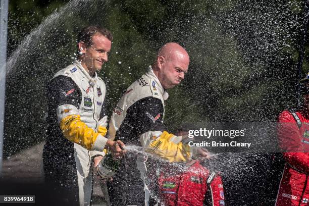 Antonio Garcia, of Spain and Jan Magnussen, of Denmark, celebrate after winning the Michelin GT Challenge WeatherTech SportsCar Series race at...