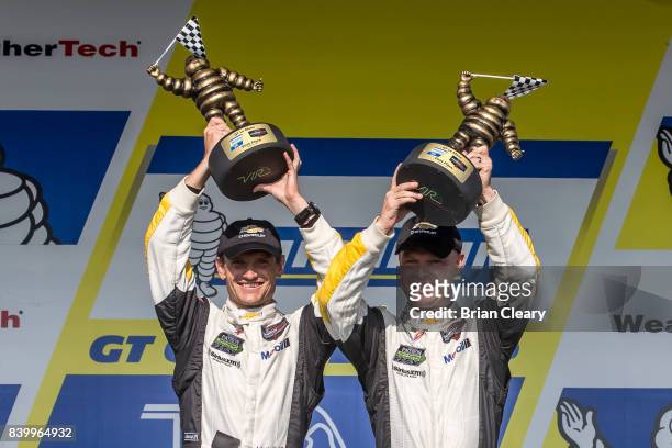 Antonio Garcia, of Spain and Jan Magnussen, of Denmark, celebrate after winning the Michelin GT Challenge WeatherTech SportsCar Series race at...