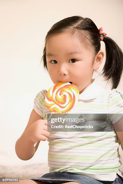 portrait of a girl eating a lollipop - pigtail lollipop stock pictures, royalty-free photos & images