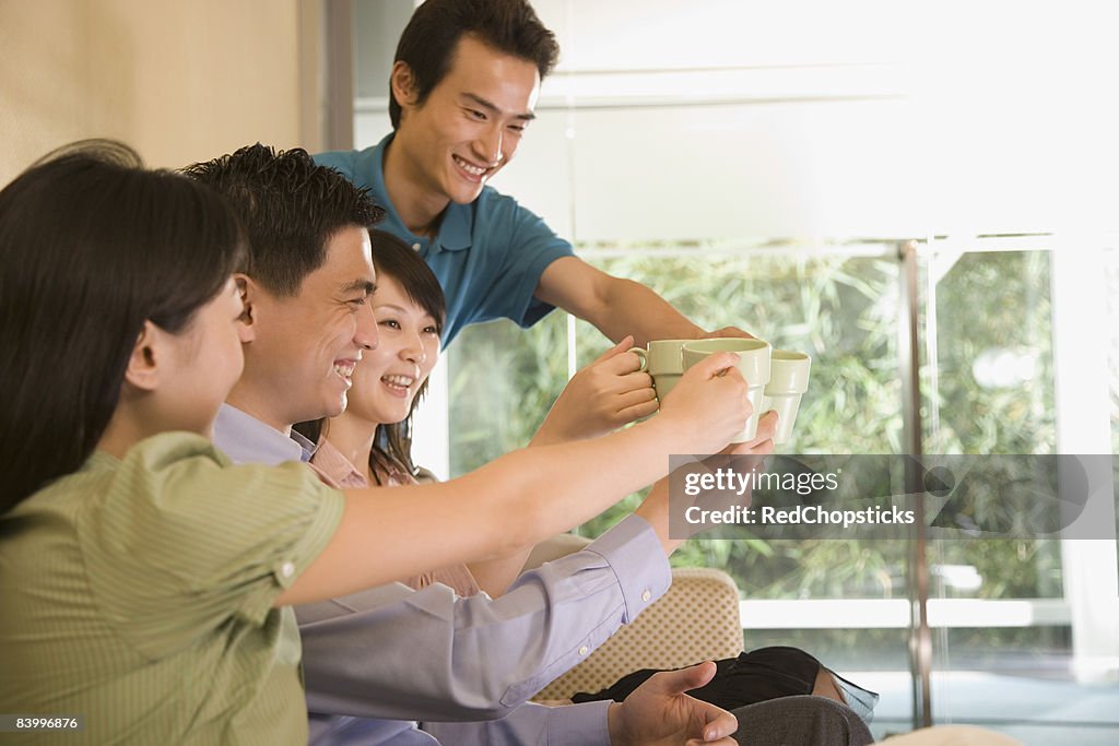 Two young men and two young women toasting with coffee cups