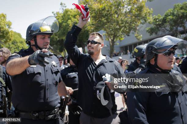 Supporter of President Trump is escorted out of MLK Jr. Park by police after being surrounded by anti-Trump protesters on August 27, 2017 in...