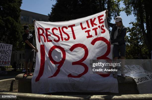 Protesters hold a banner reading "Resist Like It's 1933" during demonstrations at Civic Center Park, responding to the cancelled No to Marxism rally,...