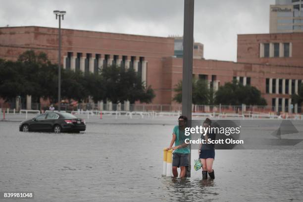 Grant Lu and Naomi Pringle stand in a flooded parking lot on the campus of Rice University afer it was inundated with water from Hurricane Harvey on...