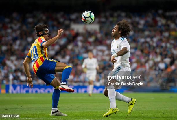 Marcelo of Real Madrid CF is challenged by Nacho Vidal of Valencia CF during the La Liga match between Real Madrid CF and Valencia CF at Estadio...