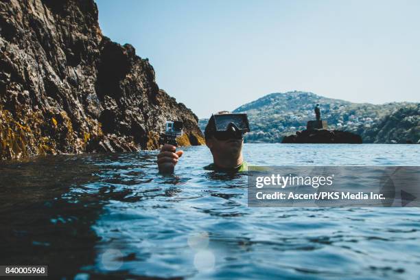 Male Diver Surfaces with mask, GoPro camera