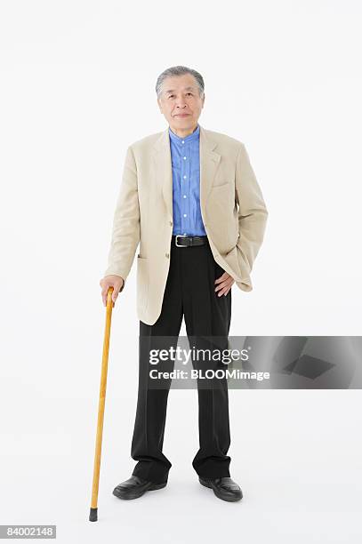 portrait of senior man with cane, studio shot - cane ストックフォトと画像