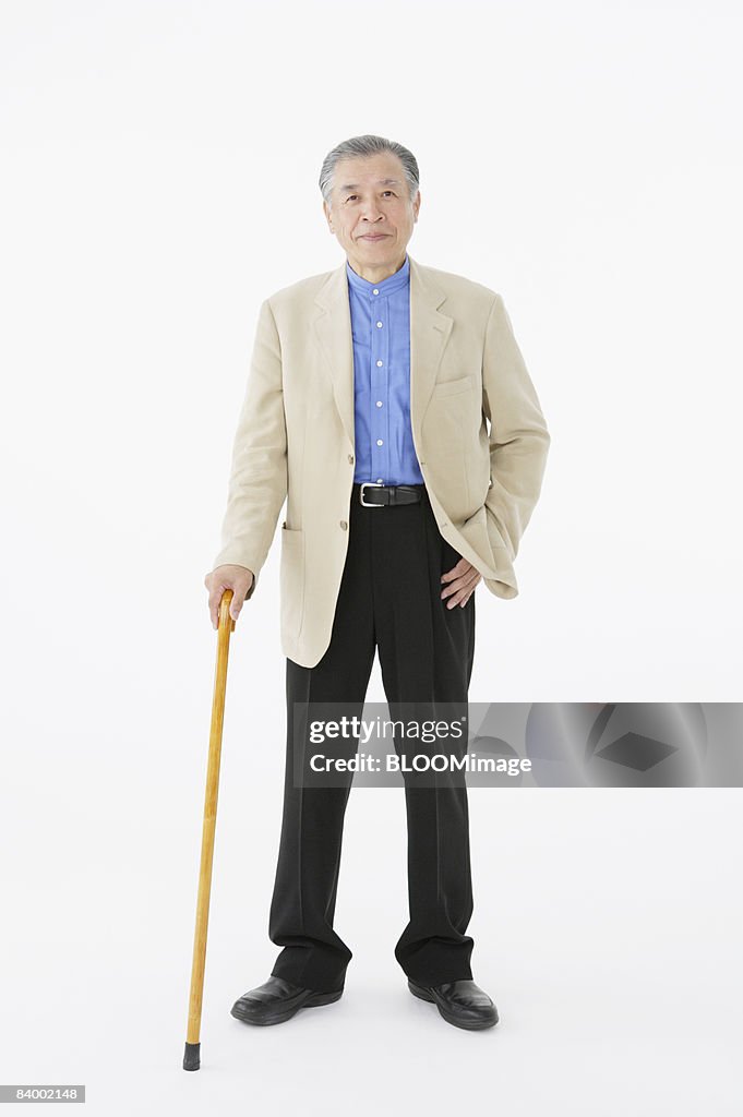Portrait of senior man with cane, studio shot