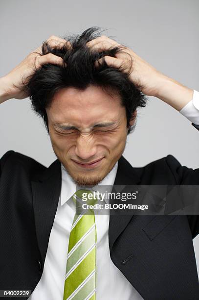 portrait of businessman with hands on head, eyes closed, close-up, studio shot - 手を顔にやる ストックフォトと画像
