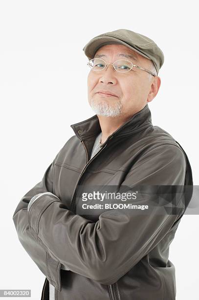 portrait of senior man with arms folded, wearing hat and glasses, close-up, studio shot - portrait close up loosely stock pictures, royalty-free photos & images