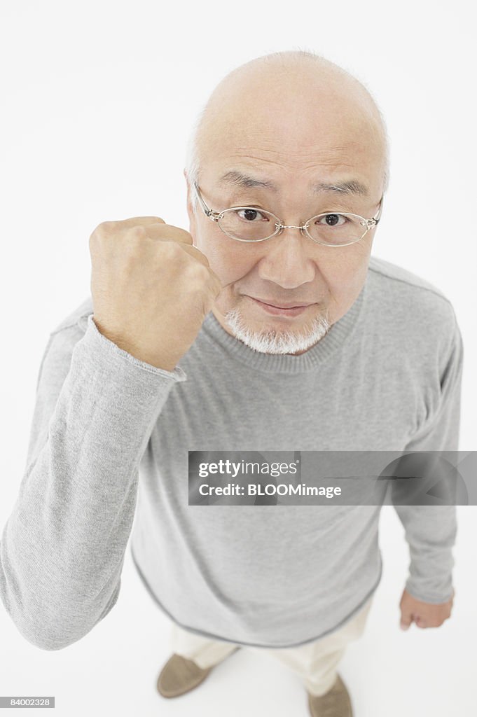 Portrait of senior man clenching fist, high angle view, studio shot