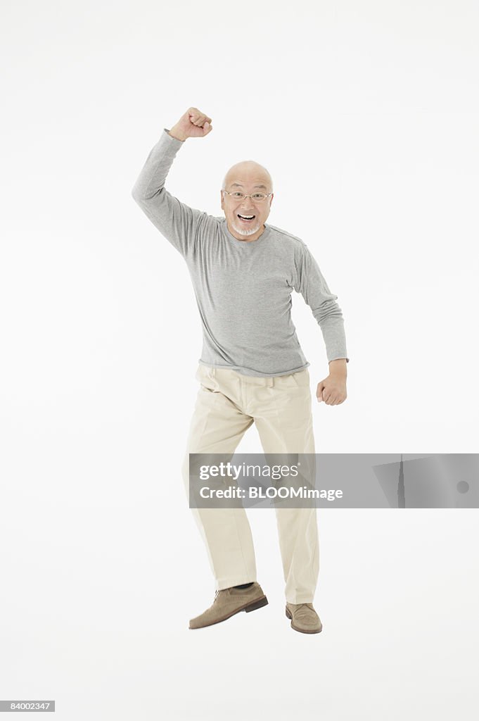 Portrait of senior man raising fist, studio shot