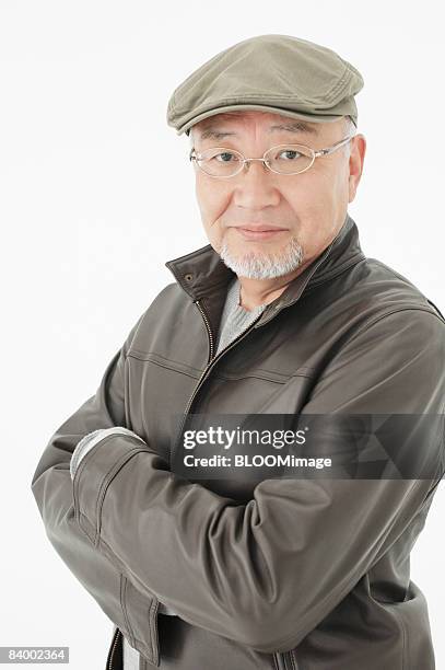 portrait of senior man with arms folded, wearing hat and glasses, close-up, studio shot - portrait close up loosely stock pictures, royalty-free photos & images