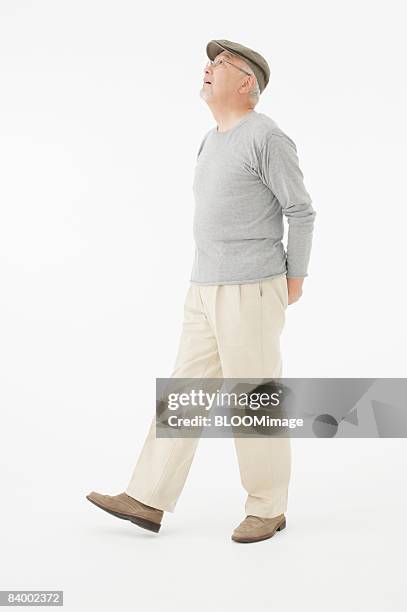 portrait of senior man clasping hands behind back, studio shot - japanese old man foto e immagini stock