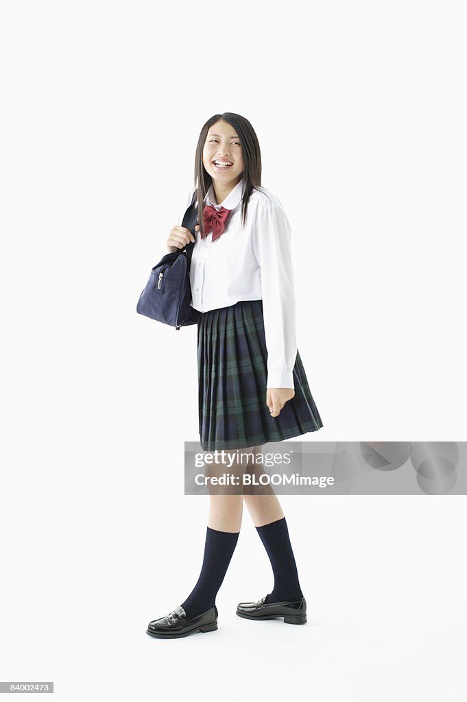 Portrait of female student holding bag, studio shot