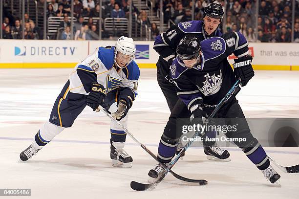 Jay McClement of the St. Louis Blues fights for the puck at center ice against Oscar Moller and Raitis Ivanans of the Los Angeles Kings during the...