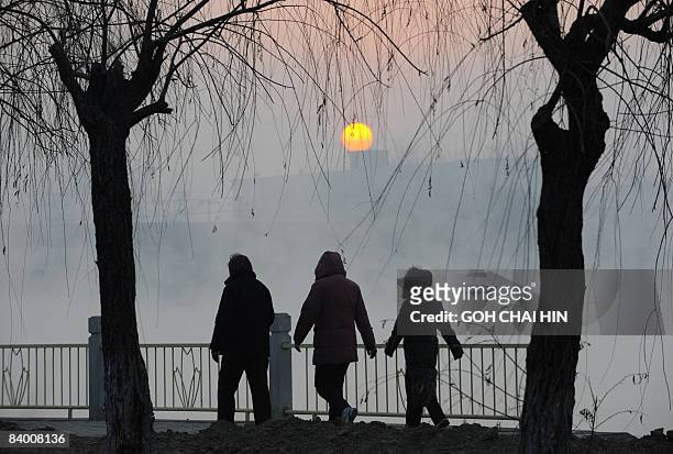 Chinese residents walk along a canal early in the morning in Beijing on December 12, 2008. Beijing, one of the most polluted cities in the world, has...
